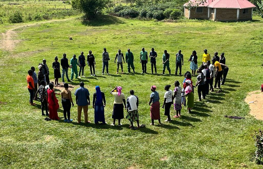 Group of people stands in a circle on a green land