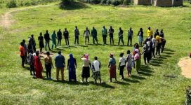 Group of people stands in a circle on a green land